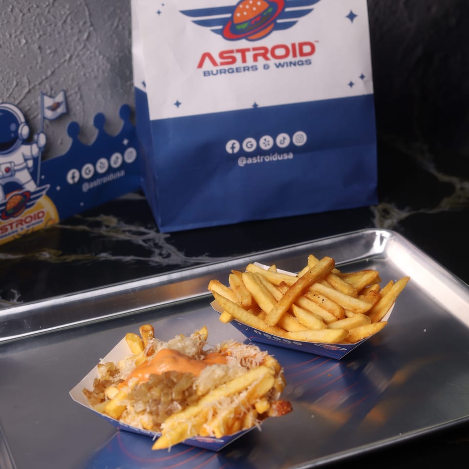 Two servings of fries, one plain and one loaded with cheese and sauce, on a metal tray.